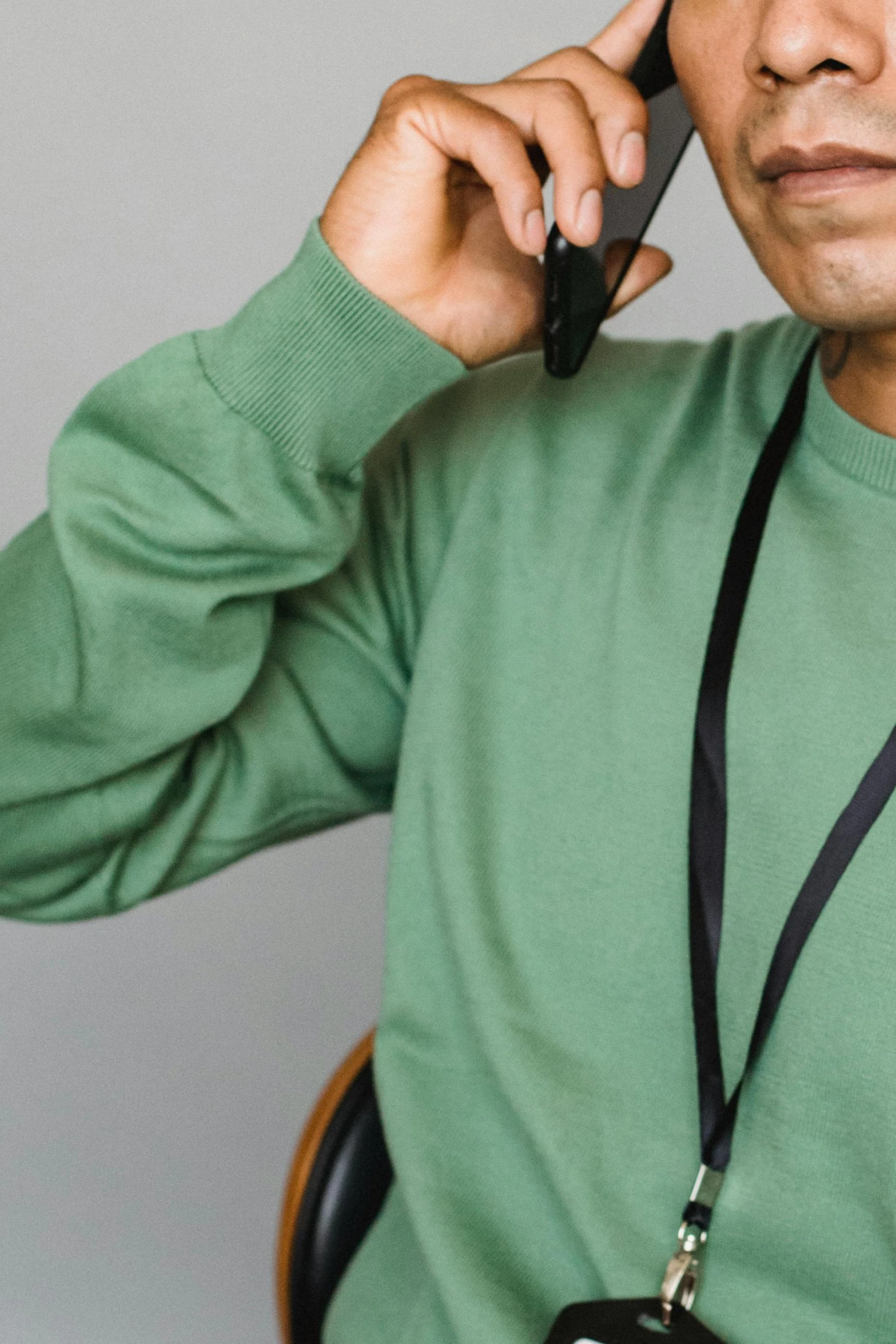 a man in a green shirt talking on a cell phone, collar and leash, wearing sweatshirt, no - text no - logo, uncrop