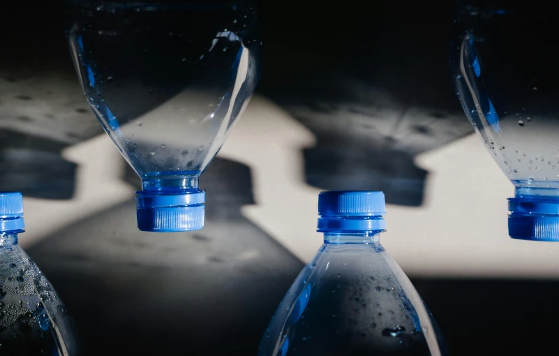 a group of water bottles sitting next to each other, pexels contest winner, hyperrealism, black-water-background, blue, morning light, thumbnail