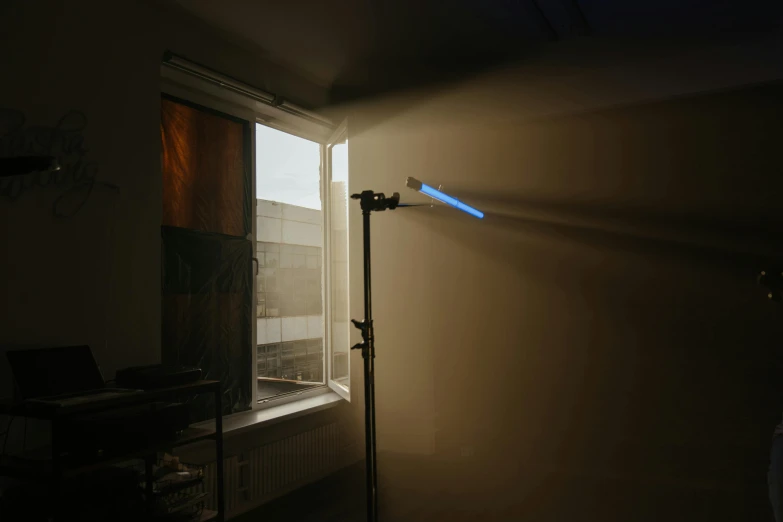 a lamp sitting next to a window in a room, inspired by Elsa Bleda, light and space, holding a blue lightsaber, experimental studio light, spotlight at a 90 degree angle, diffuse overhead lighting