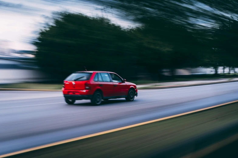 a red car driving down a road with trees in the background, a picture, unsplash, renaissance, sprinting, technical, 1 2 9 7, performance