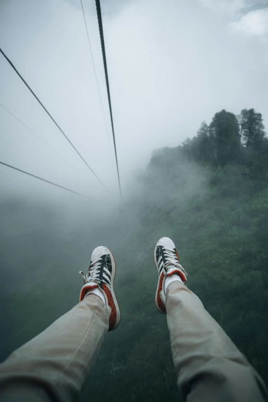 a person standing on top of a cable car, by Jacob Toorenvliet, sumatraism, wearing white sneakers, foggy mood, lying down, view up