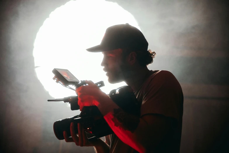 a man holding a camera in front of a light, dramatic cinematography, production ig, filmstill, **cinematic