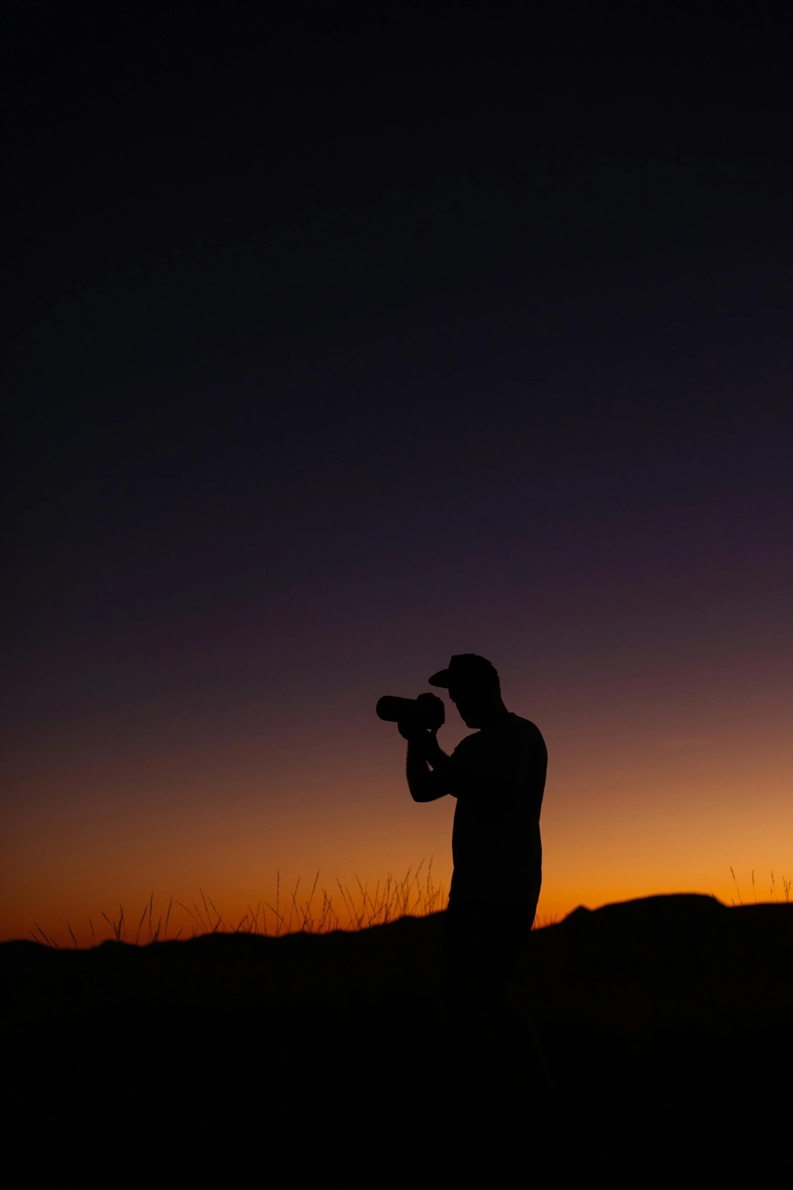 a man that is standing in the grass with a camera, by Dennis Ashbaugh, pexels, silhouette over sunset, space photography, medium format. soft light, night time photograph