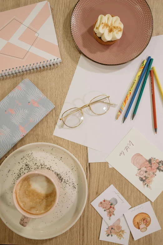 a cup of coffee sitting on top of a wooden table, process art, pink glasses, pencils, curated collections, square glasses