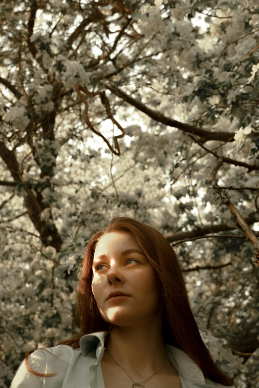 a woman standing in front of a tree, inspired by Elsa Bleda, renaissance, looking up at the camera, ( redhead, solarised, arbor