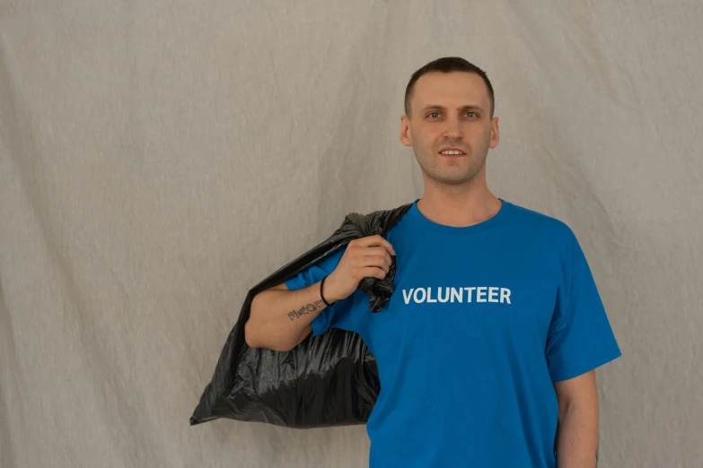 a man in a blue shirt holding a black bag, pexels contest winner, plasticien, wearing a t-shirt, avatar image, rubbish, official product image