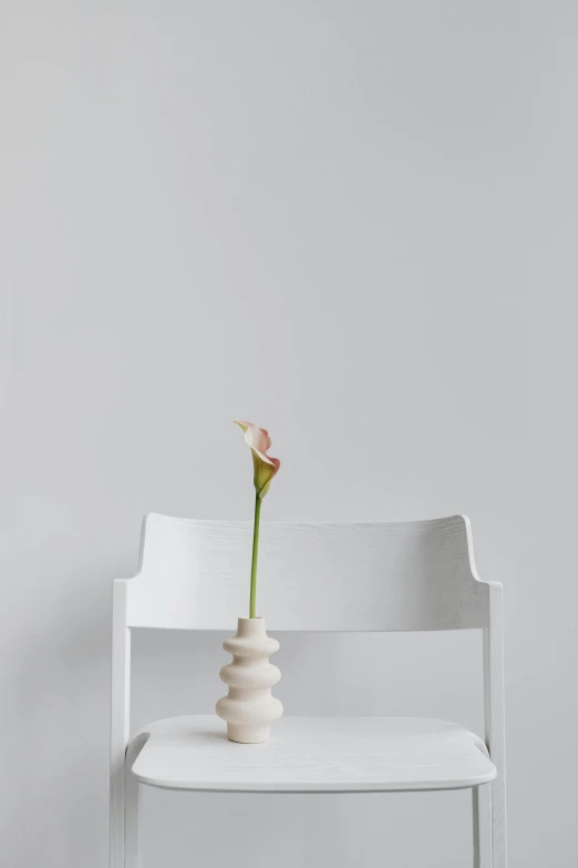 a white chair with a flower sitting on top of it, a marble sculpture, unsplash, minimalism, lily frank, ad image, multiple stories, tall