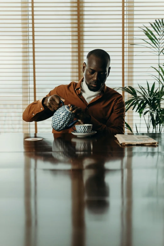 a man sitting at a table in front of a laptop, an album cover, inspired by Barthélemy Menn, pexels contest winner, tea ceremony scene, mc ride, tailored clothing, tense