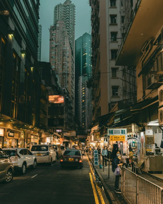 a street filled with lots of traffic next to tall buildings, by Patrick Ching, pexels contest winner, humid evening, kings row in the background, 90s photo, alleys