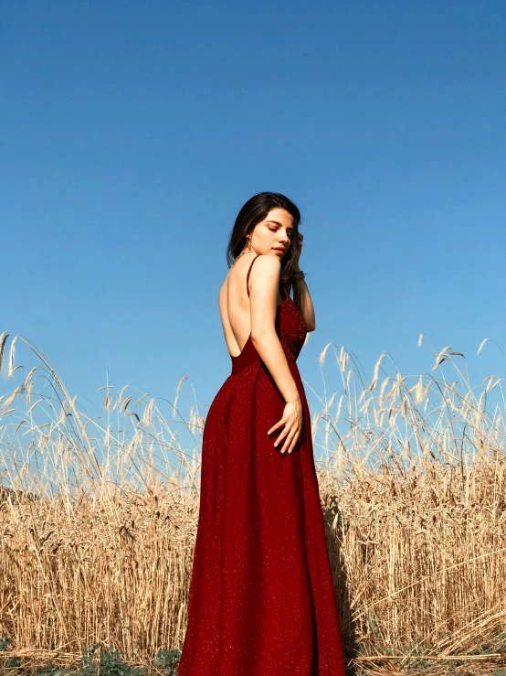 a woman in a red dress standing in a field, an album cover, pexels contest winner, hailee steinfeld, back slit, 15081959 21121991 01012000 4k, maroon red