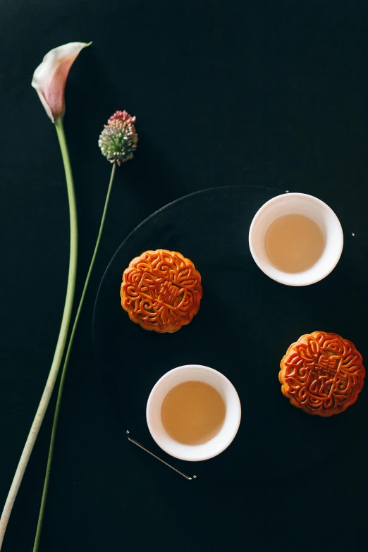 a couple of cups of tea sitting on top of a table, a still life, inspired by Gu An, trending on unsplash, crispy buns, intricate carving, thumbnail, with lotus flowers