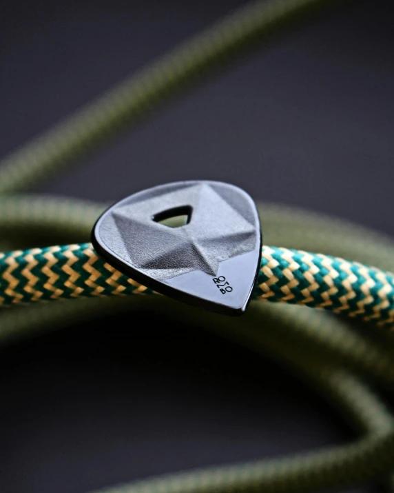 a close up of a guitar pick on a rope, made of high tech materials, threyda, thick set features, climber