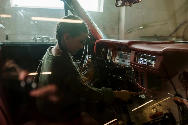 a man sitting in the driver's seat of a car, inspired by Elsa Bleda, in a workshop, still from stranger things movie, an intricate, restoration