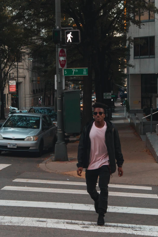 a man walking across a crosswalk on a city street, an album cover, by Washington Allston, unsplash, happening, wearing a pastel pink hoodie, low quality photo, high rises, posing for a picture