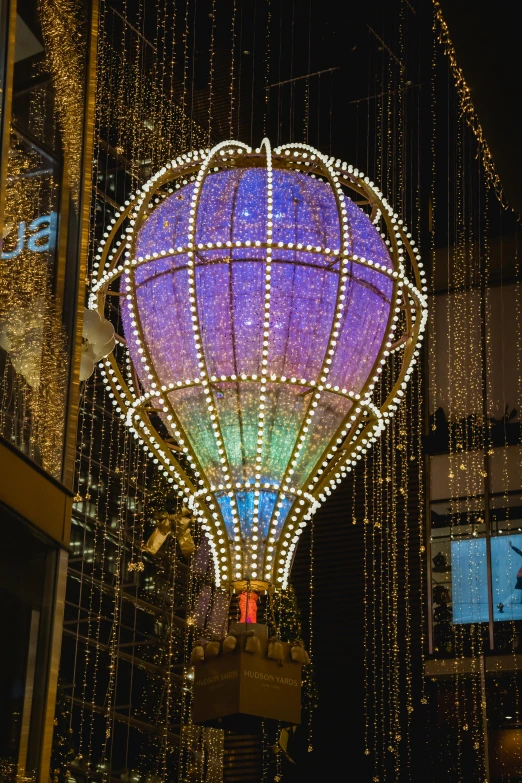 a hot air balloon hanging from the side of a building, inspired by Jeff Koons, pexels contest winner, art nouveau, christmas lights, time square, crystals enlight the scene, square