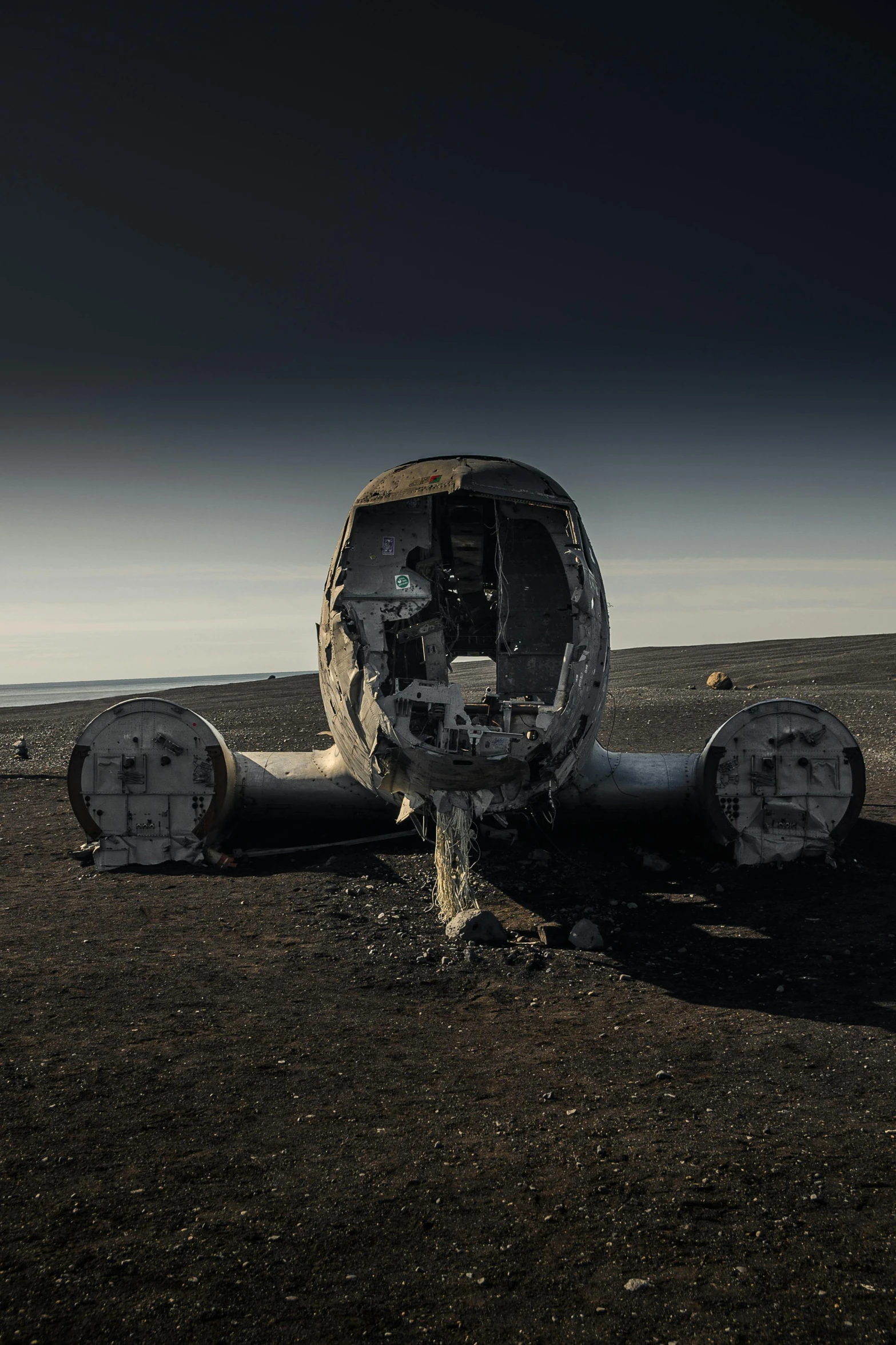 an airplane sitting on top of a dirt field, inspired by Filip Hodas, unsplash contest winner, land art, pre - ww 1 submarine, black sand, destroyed body, robot made of jet parts