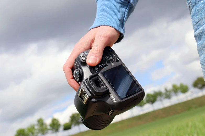 a person holding a camera in their hand, photograph, focus on the sky, back towards camera, on display