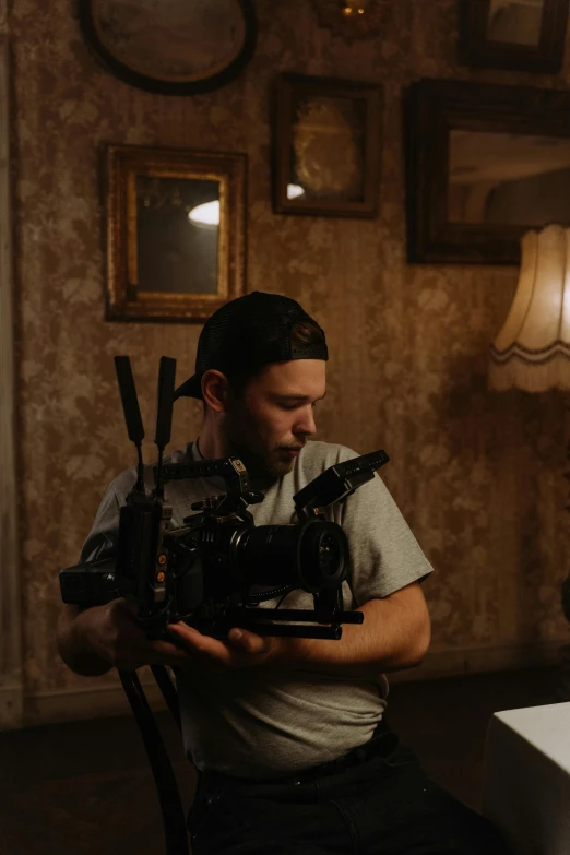 a man sitting in a chair holding a camera, cinematic arthouse, low light cinematic, back towards camera, on set