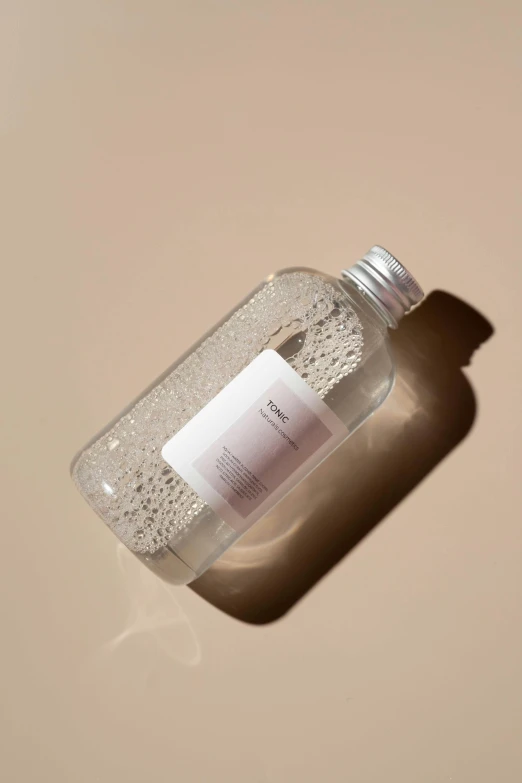 a bottle of hand sanitizer sitting on a table, by Nina Hamnett, dwell, detailed product image, sand particles, bubble bath