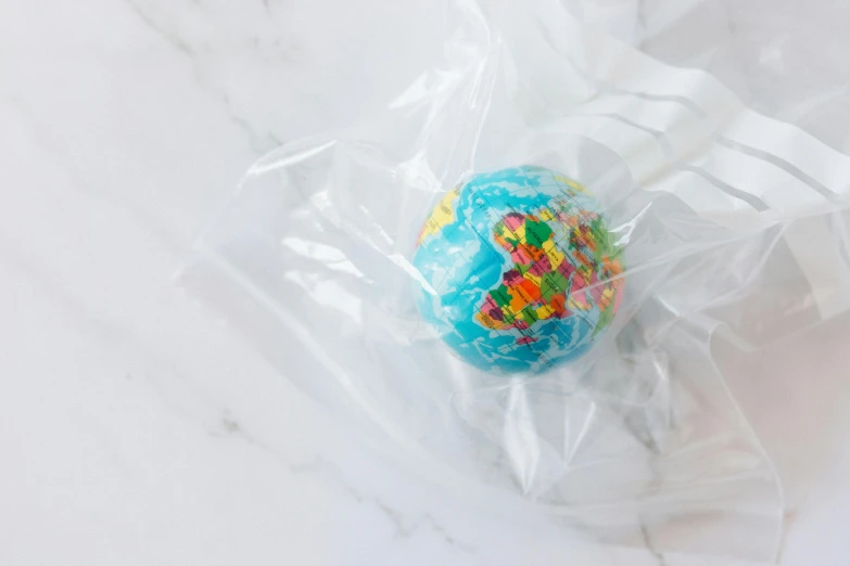 a close up of a doughnut in a plastic bag, inspired by Damien Hirst, unsplash, earth globe on top, made of lollypops, limited edition, inside a marble