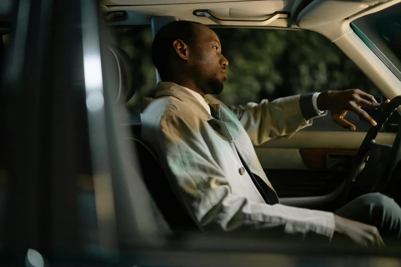 a man sitting in the driver's seat of a car, happening, jemal shabazz, **cinematic, rectangle, evening mood