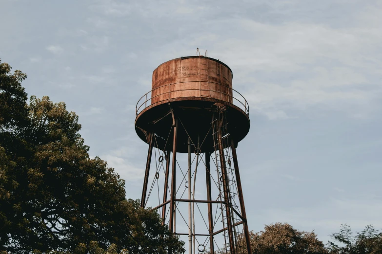 a rusted water tower with trees in the background, inspired by Elsa Bleda, unsplash contest winner, vsco, vessels, blank, brown