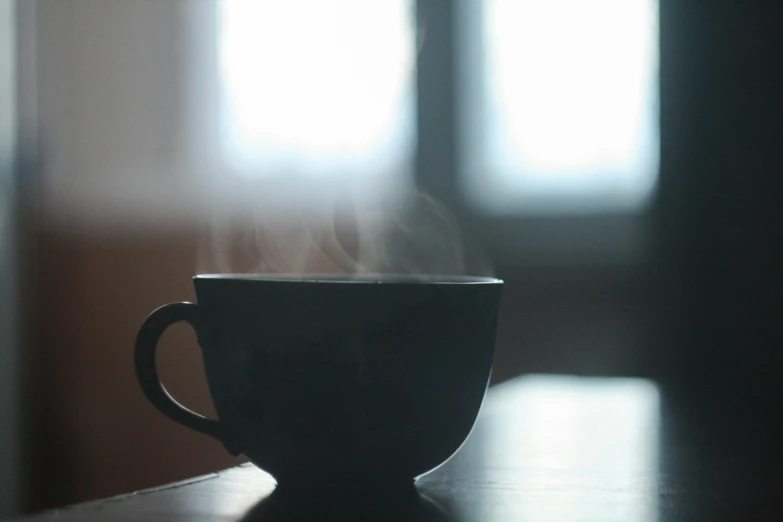 a close up of a cup of coffee on a table, pexels contest winner, romanticism, dark hazy room, soft smoke, natural light outside, black