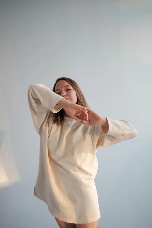 a woman in a white dress posing for a picture, inspired by Kim Tschang Yeul, unsplash, happening, wearing sweatshirt, arms extended, performance, wear's beige shirt