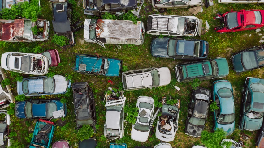 a bunch of old cars sitting on top of a lush green field, by Adam Marczyński, trending on unsplash, auto-destructive art, dji top down view, junk yard, ai weiwei and gregory crewdson, scattered rubbish and debris