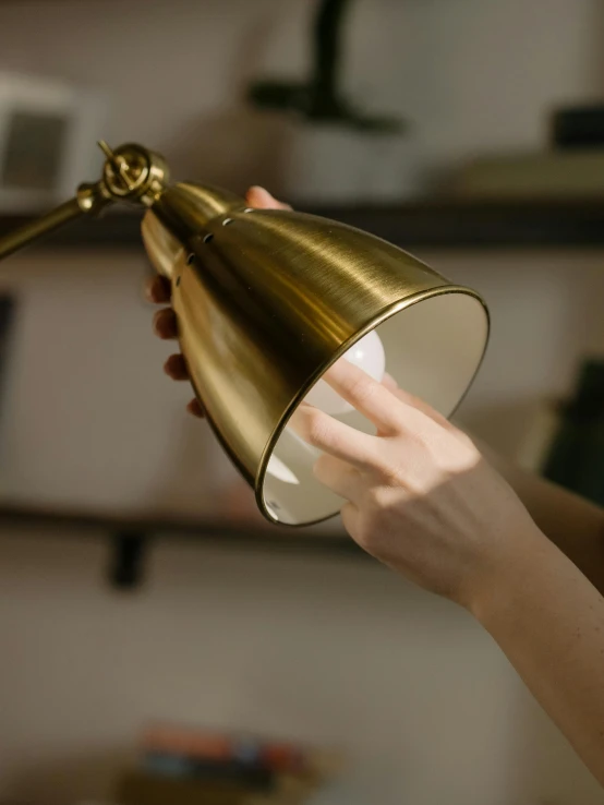 a close up of a person holding a lamp, happening, metallic brass accessories, angled shot, vista view, cinematic counter light
