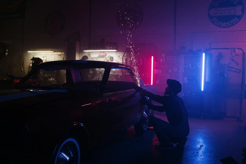 a man working on a car in a garage, an album cover, inspired by Elsa Bleda, holding an activated lightsaber, red and blue black light, [ cinematic, cinestill eastmancolor