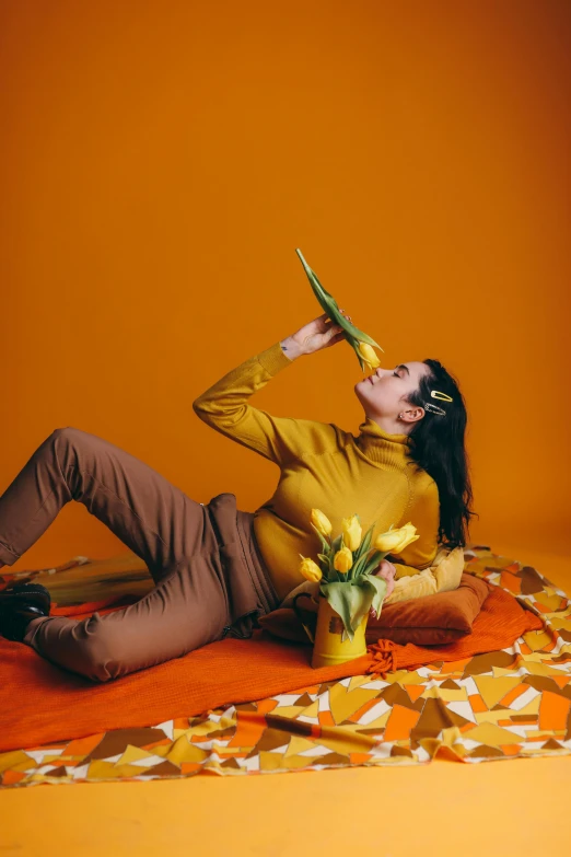 a woman laying on the ground with a pair of scissors in her hand, an album cover, pexels contest winner, aestheticism, yellow and orange color scheme, eating cheese, full body potrait holding bottle, blooming