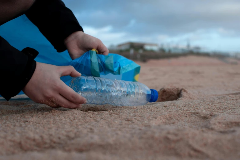 a person putting a plastic bottle in the sand, profile image, image