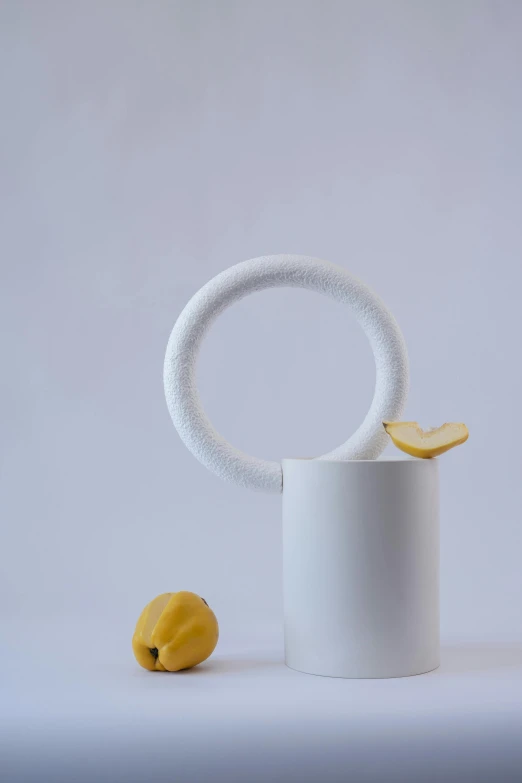 a white cup sitting on top of a table next to a lemon, an abstract sculpture, unsplash, new sculpture, hoop earrings, white soft leather model, ornamental halo, vase