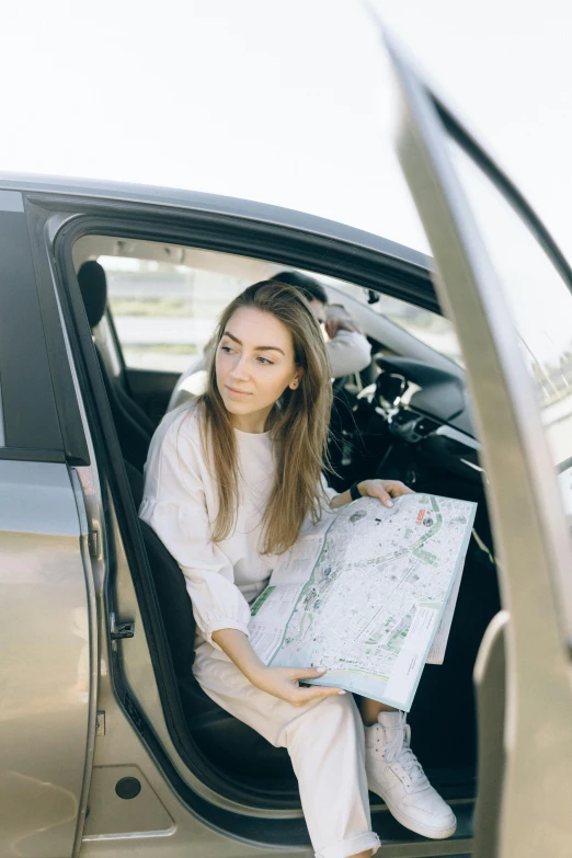a woman sitting in a car holding a map, happening, complex features, slightly minimal, helpful, white map library