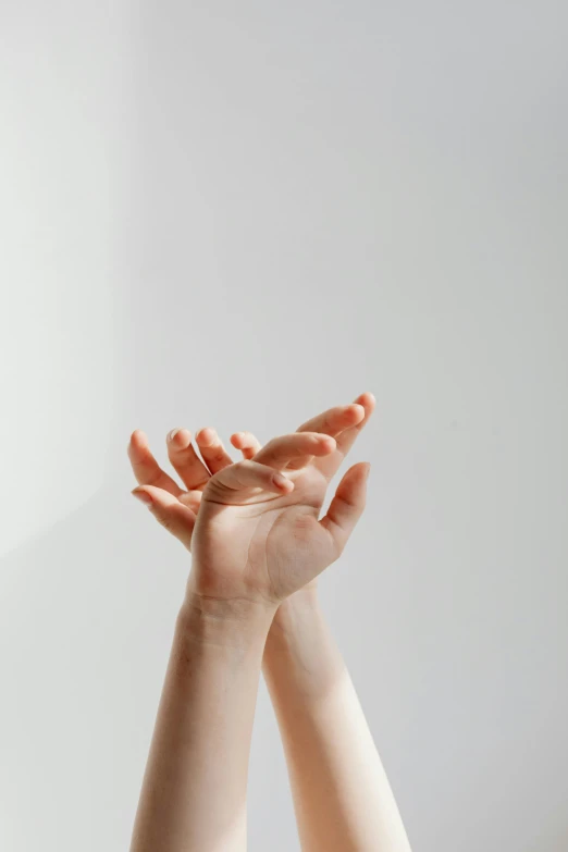 a woman holding her hands up in the air, trending on pexels, minimalism, on a gray background, glossy surface, healing, on a white background