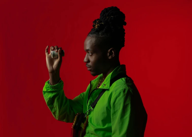 a person standing in front of a red background, an album cover, trending on pexels, ( ( dark skin ) ), mana shooting from his hands, red and green hour, linus sebastian