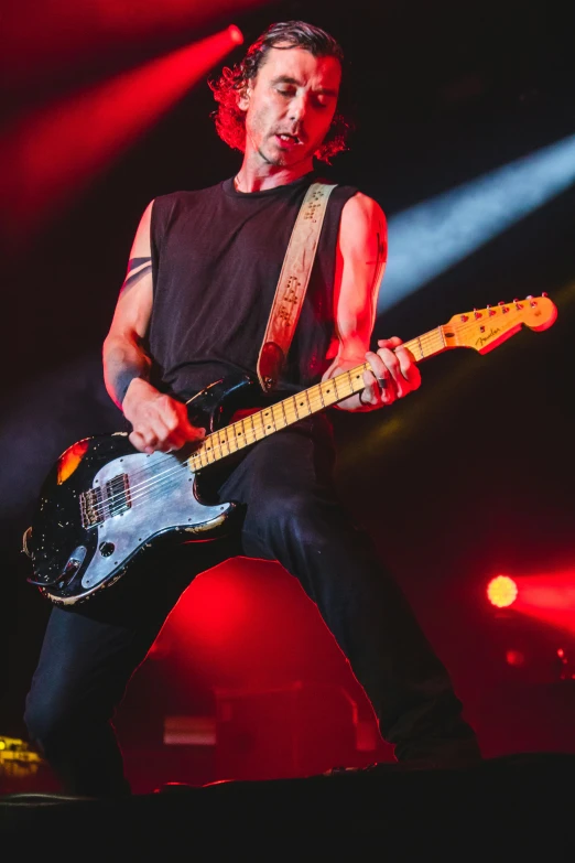 a man that is playing a guitar on a stage, an album cover, pexels, antipodeans, slightly muscular, octane fender, he is wearing a black t-shirt, ✨🕌🌙