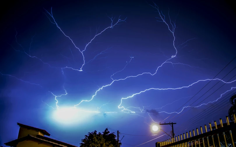 a sky filled with lots of lightning next to a building, dramatic white and blue lighting, 300mm, unsplash photo contest winner, electric arc