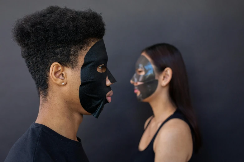 a woman with a black mask on her face next to a man with a black mask on his face, by Nina Hamnett, silicone skin, varying ethnicities, gen z, facing sideways