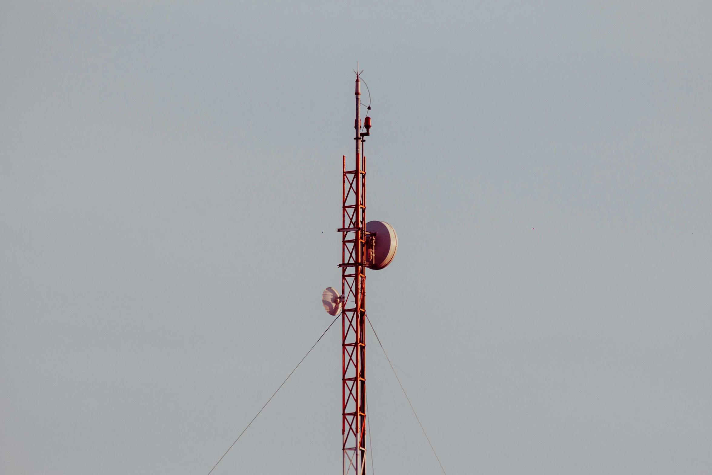 a tower with a cell phone on top of it, pexels, 8k 50mm iso 10, with long thin antennae, pink and red color scheme, satellite