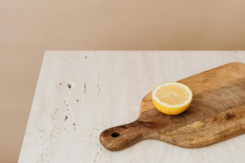 a wooden cutting board with a slice of lemon on it, inspired by Agnes Martin, trending on pexels, minimalism, white travertine terraces, neutral light, chefs table, looking to his left