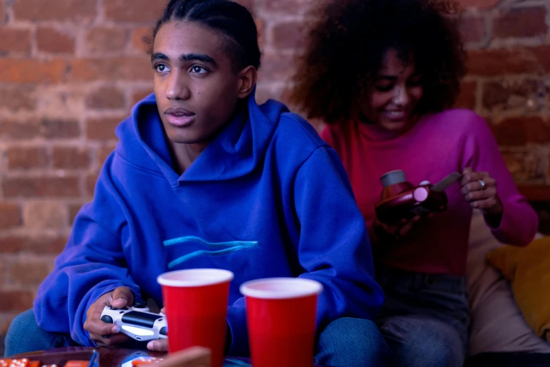 a man and a woman sitting on a couch playing a video game, trending on pexels, graffiti, imaan hammam, awkwardly holding red solo cup, tense look, people sitting at tables