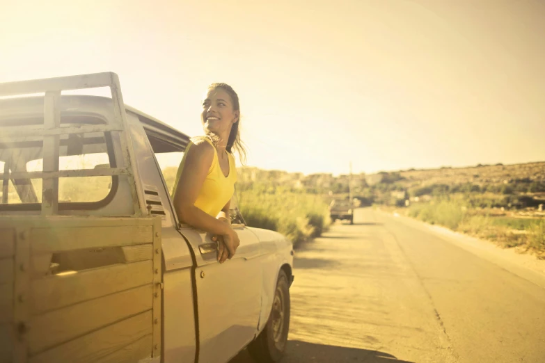 a woman sitting in the back of a pick up truck, pexels contest winner, yellow tint, summer sunlight, near the beach, mechanic