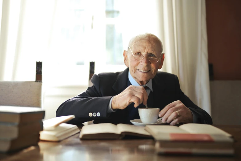 a man sitting at a table with a cup of coffee, a portrait, inspired by John Stuart Ingle, pexels contest winner, rudolf weisse, elder, having a great time, 15081959 21121991 01012000 4k