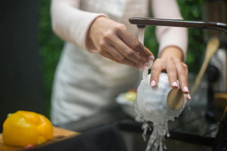 a woman washing her hands in a kitchen sink, pexels, ice - carving, peeled lemons, mechanised, dry ice