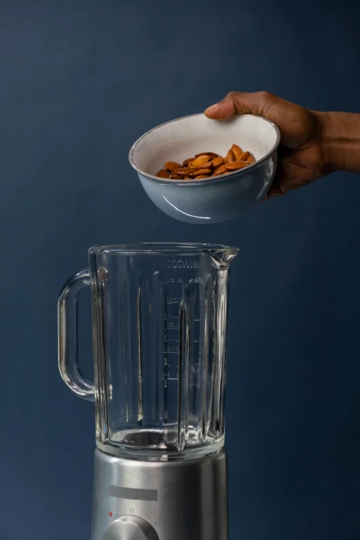 a person pouring almonds into a blender, process art, grey, detailed product image, tall shot, bowl