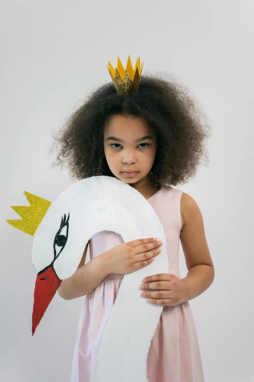 a young girl in a pink dress holding a paper swan, an album cover, shutterstock contest winner, crown made of felt, in front of white back drop, kids place, at a fashion shoot