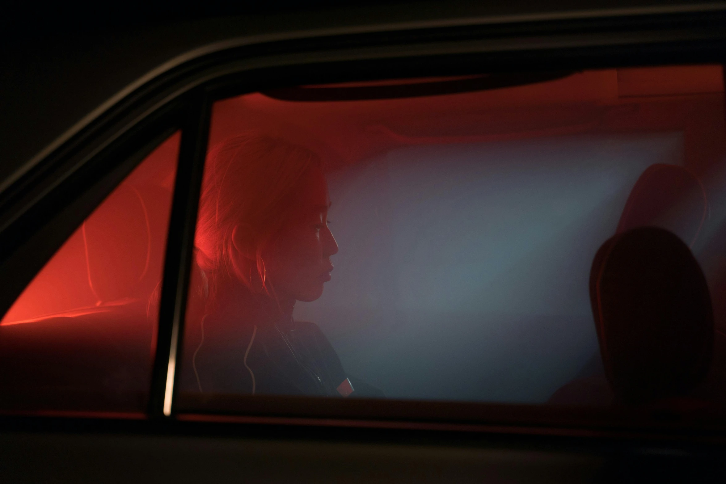 a man sitting in the passenger seat of a car, inspired by Nan Goldin, photorealism, red neon, film still of emma watson, todd hido, cinematic shot ar 9:16 -n 6 -g