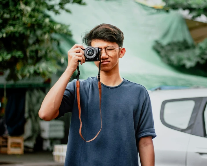 a man taking a picture with a camera, pexels contest winner, wearing a dark blue polo shirt, asian male, avatar image, teenage boy